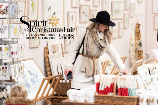 Visitor browsing festive stalls and artwork at the Spirit of Christmas Fair 2025 at Olympia London, hosted by House & Garden