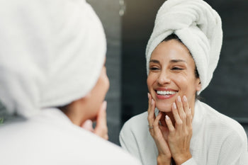 Woman applying skincare in mirror looking fresh and awake
