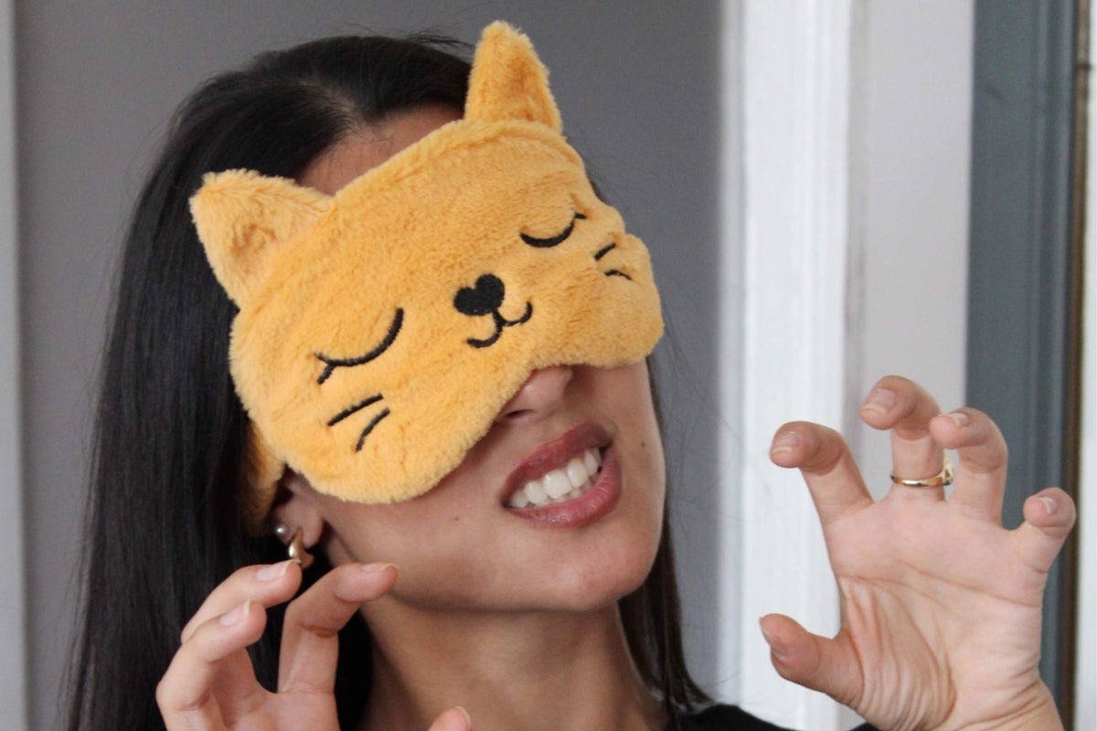Woman wearing a plush orange cat sleep mask by SMUG, playfully posing with a claw gesture for a fun Halloween-inspired look