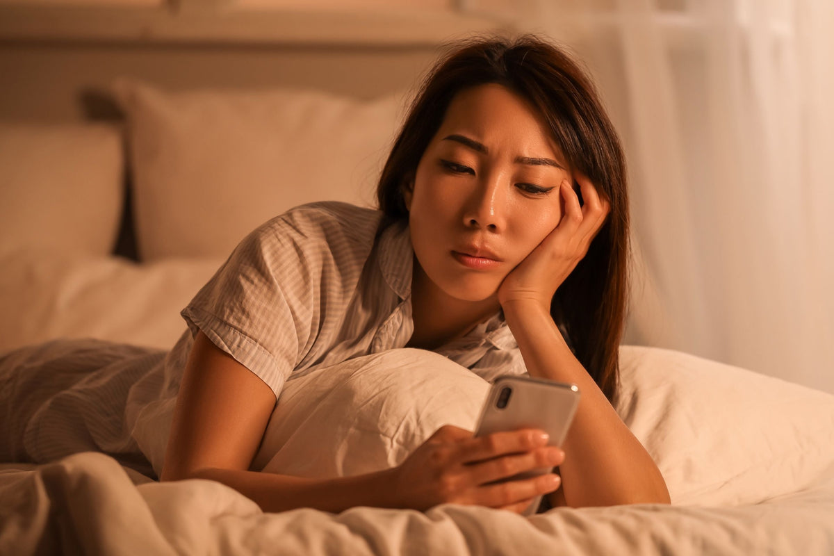 Woman struggling to sleep checking her phone
