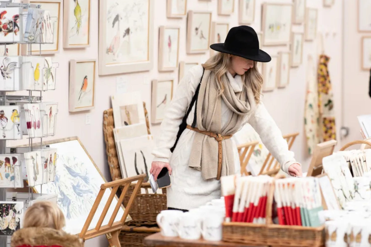 Visitor browsing festive stalls and artwork at the Spirit of Christmas Fair 2025 at Olympia London, hosted by House & Garden